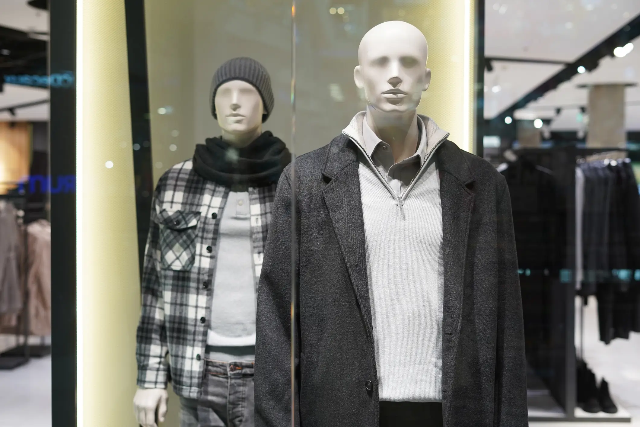 Two mannequins wearing winter clothing in store.