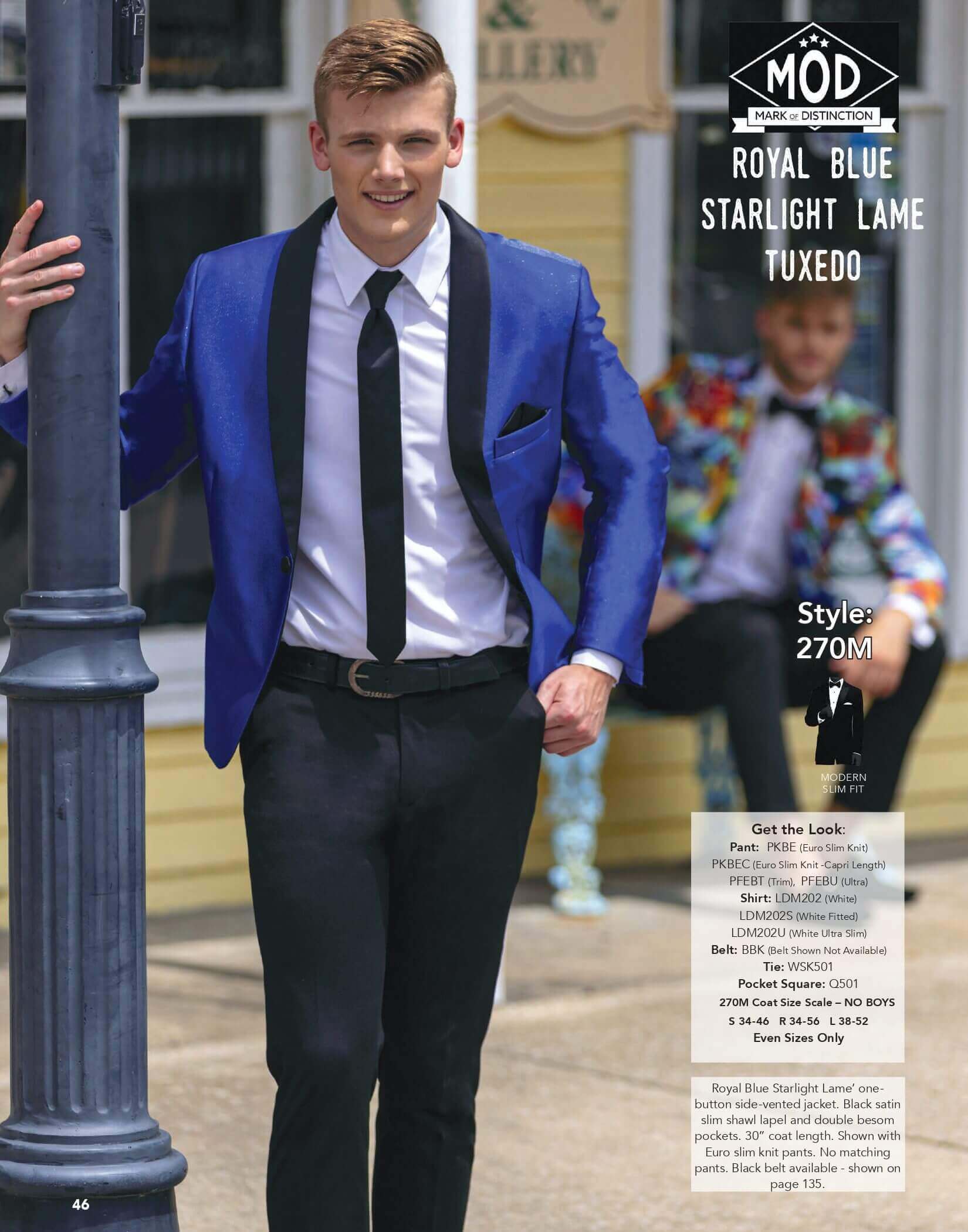 Man in royal blue tuxedo smiling outdoors.