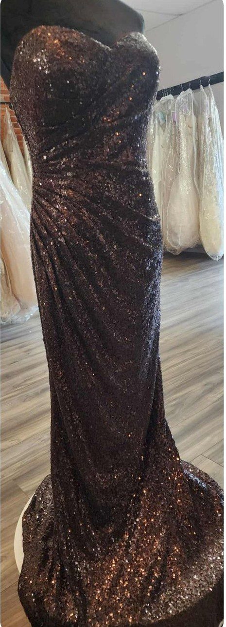 Elegant black sequin evening gown on wooden floor.