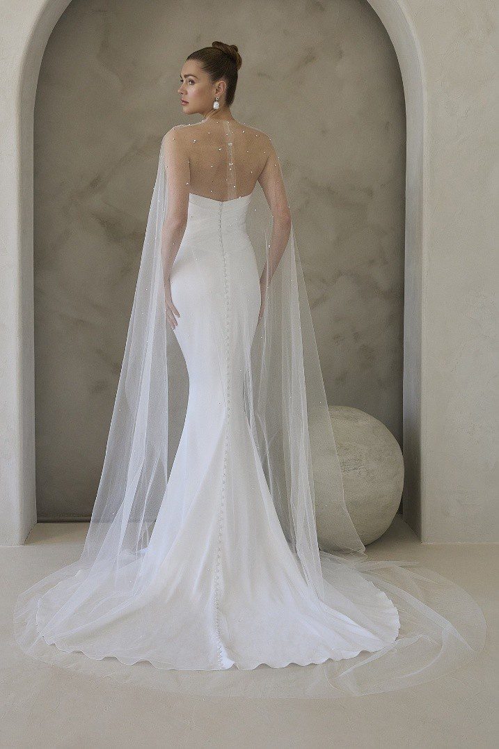 Elegant white mermaid wedding dress with sheer cape detail.