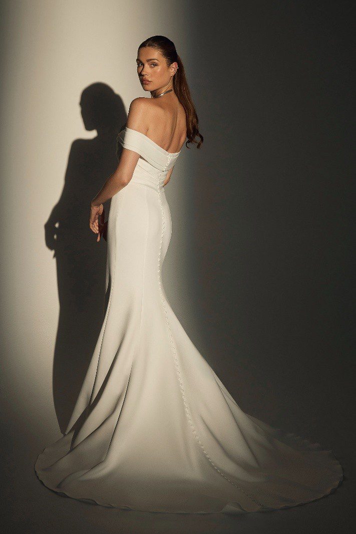 Woman in elegant white off-shoulder gown casting a shadow.