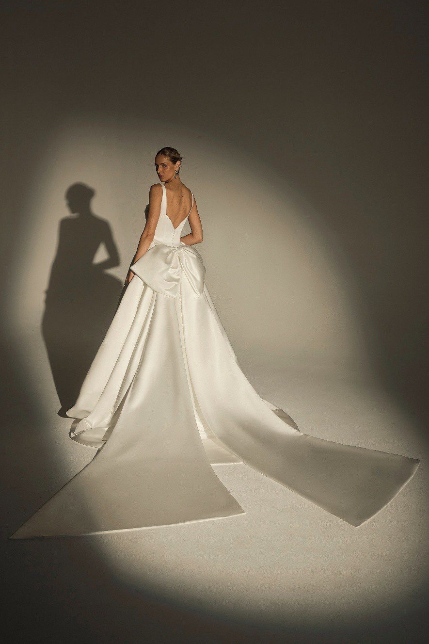 Elegant bride in a long white wedding gown with a dramatic train.