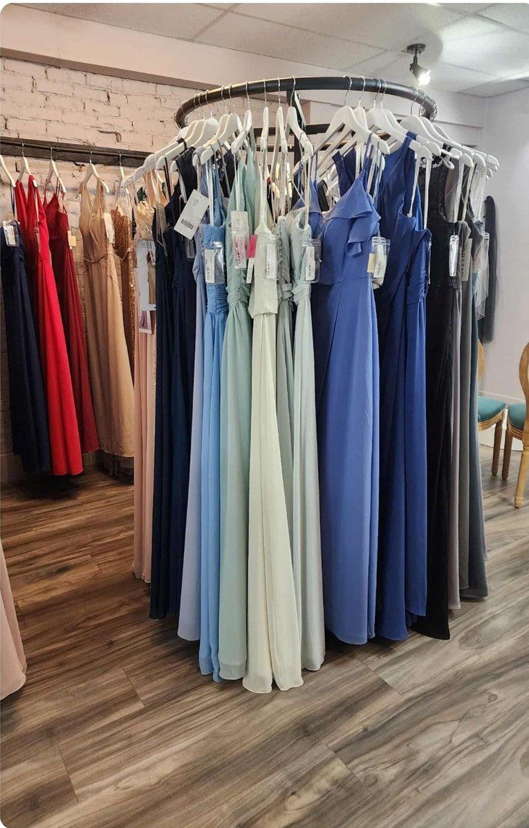 A rack of elegant bridesmaid dresses in various pastel and blue shades.
